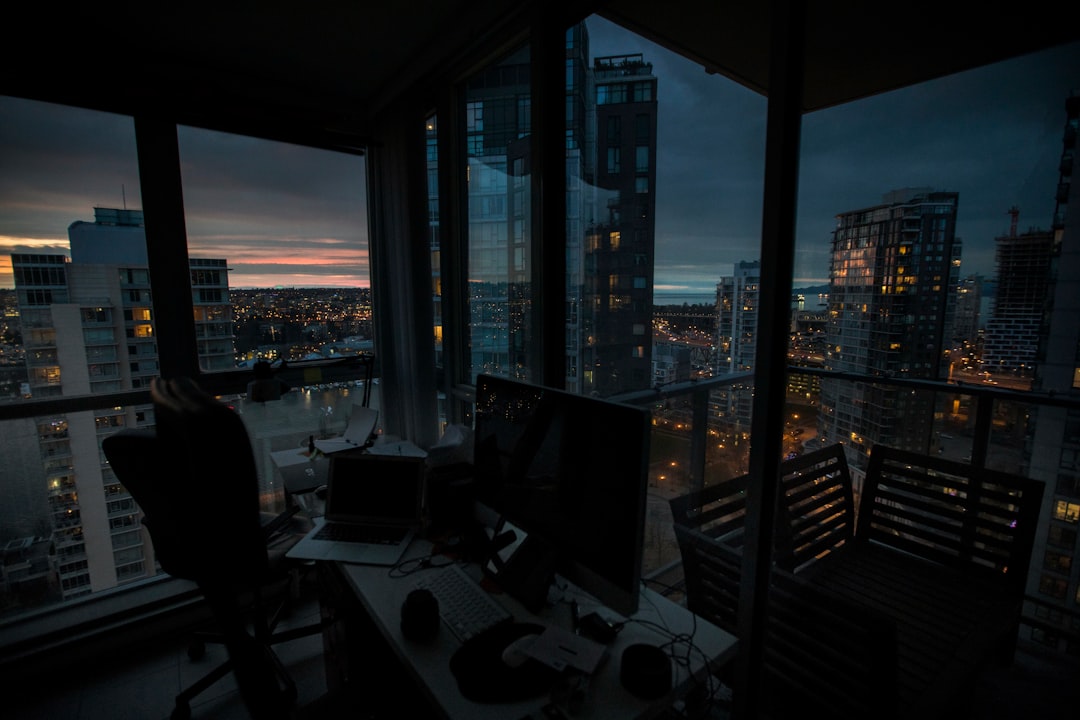 a desk with a computer on top of it in front of a window