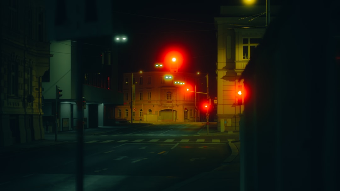 Red traffic lights glow at a dark city intersection.